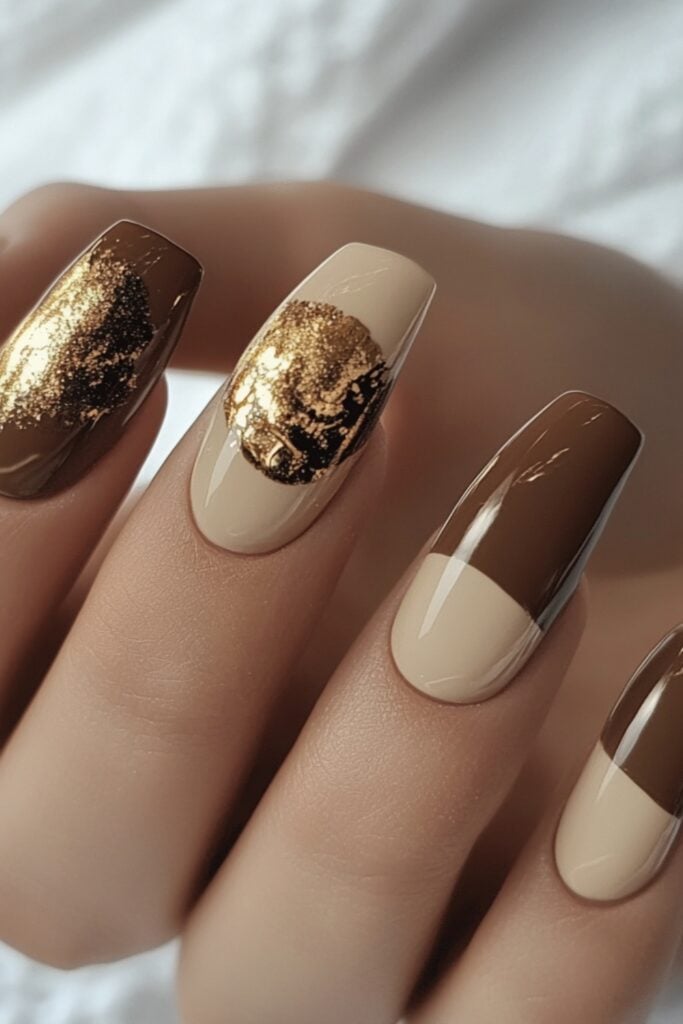 Hands with nude-colored nails in shades of blush and beige, adorned with subtle gold foil accents, creating a clean and sophisticated look.