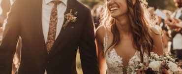 Image of a newlywed couple walking hand-in-hand through a scenic backdrop, with a personalized wedding arch behind them and joyous guests celebrating in the background.