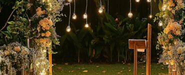 A beautifully decorated backyard with fairy lights, a wooden arch adorned with flowers, and chairs set up for a wedding ceremony, evoking an intimate and magical atmosphere.