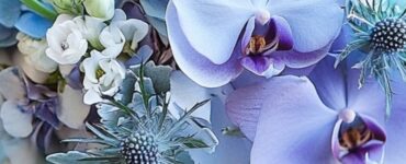 A close-up of an elegant blue wedding bouquet resting on a table, featuring a mix of hydrangeas, orchids, and thistles, symbolizing timeless wedding charm.