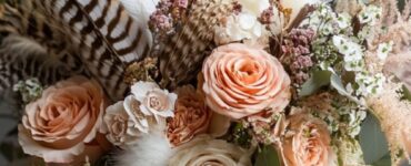 A boho wedding bouquet with a harmonious mix of textures, including feathers, romantic florals, and trailing ribbons, showcasing creative, personalized touches.