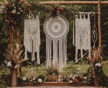 A beautifully decorated boho wedding ceremony with macramé backdrops, dreamcatchers, and greenery, set outdoors under soft, natural lighting.