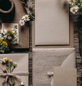Flat lay of rustic wedding invitations featuring earthy materials like burlap, kraft paper, and wildflowers for a natural theme.