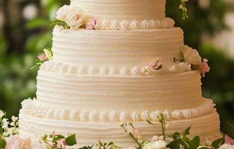 An elegant wedding cake surrounded by flowers, symbolizing simplicity and timeless charm as a centerpiece for any celebration.