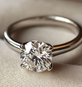 A close-up image of a classic solitaire engagement ring featuring a single sparkling diamond mounted on a sleek platinum band, symbolizing simplicity and timeless elegance.