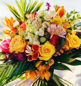 A tropical wedding bouquet with vibrant flowers and lush greenery, set against a sunny beach backdrop, symbolizing paradise-inspired wedding arrangements.