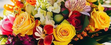 A tropical wedding bouquet with vibrant flowers and lush greenery, set against a sunny beach backdrop, symbolizing paradise-inspired wedding arrangements.