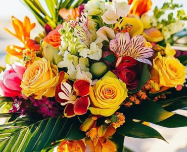 A tropical wedding bouquet with vibrant flowers and lush greenery, set against a sunny beach backdrop, symbolizing paradise-inspired wedding arrangements.