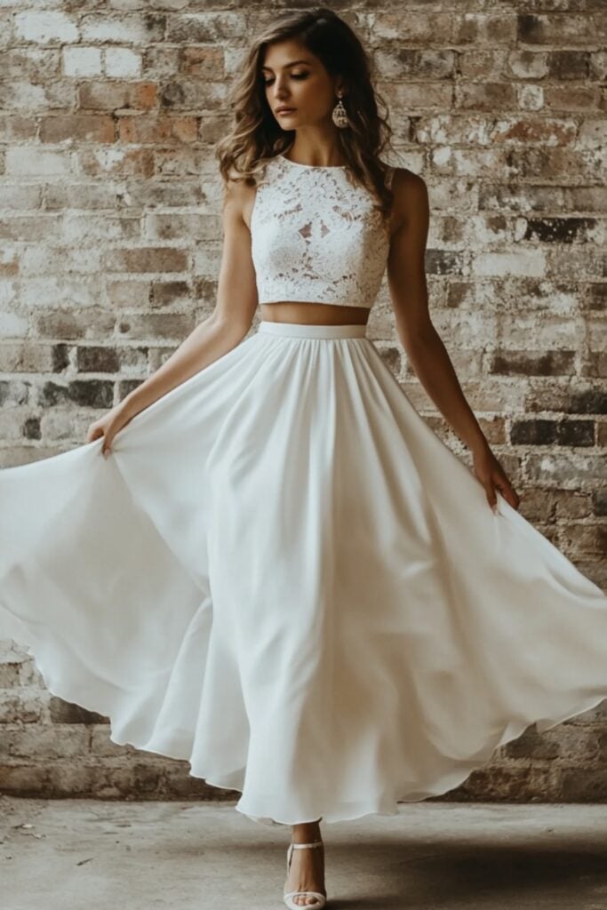 A two-piece wedding dress with a lace crop top and flowing satin skirt, styled with simple heels for a stylish yet versatile wedding ensemble.