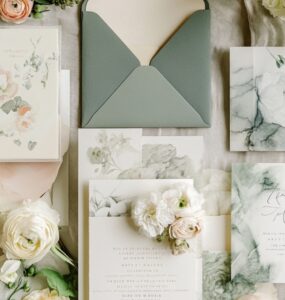 Flat lay of various wedding invitations, including acrylic, scrolls, and watercolor designs, symbolizing creativity and personalized style.
