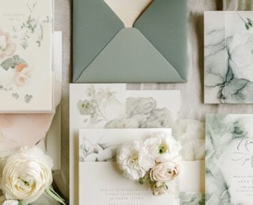 Flat lay of various wedding invitations, including acrylic, scrolls, and watercolor designs, symbolizing creativity and personalized style.