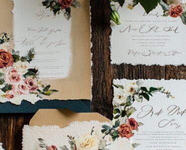 A beautifully styled backyard wedding invitation with floral designs and elegant calligraphy, set on a rustic wooden table.