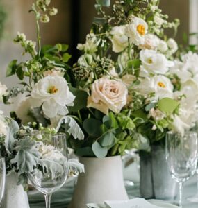 A beautifully styled wedding table with sage green elements, including linen napkins, floral arrangements, and elegant dinnerware, creating a sophisticated and serene atmosphere.