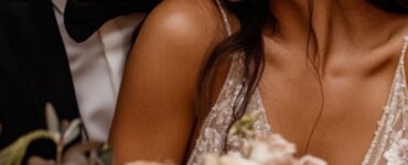 A heartwarming moment of a newlywed couple embracing at their beautifully decorated wedding reception, surrounded by warm brown hues, soft candlelight, and elegant florals.